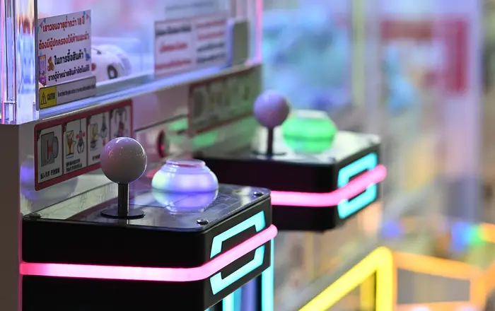 DFC 0798 Close up of illuminated arcade claw machines with glowing joysticks and neon accents