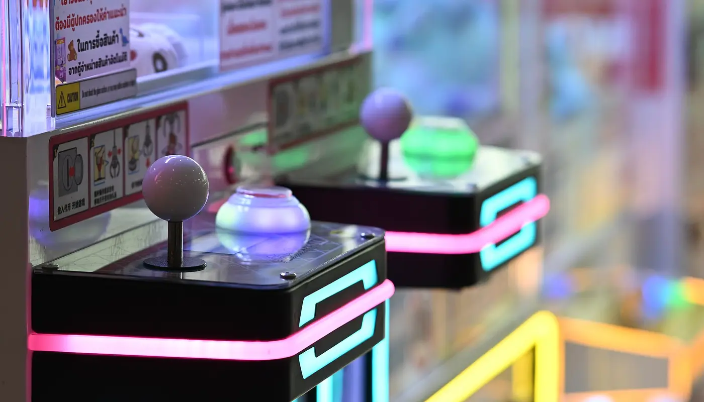 DFC 0798 Close up of illuminated arcade claw machines with glowing joysticks and neon accents